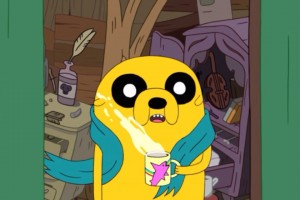 Foto de Jake el Perro de la caricatura Hora de Aventura, sosteniendo una taza de cafe mientras el fresco de la mañana pega en su cara. Por suerte tiene una bufandita azul.