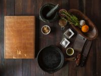 Foto de una mesa con ingredientes listos para cocinar y una tabla de cocina.