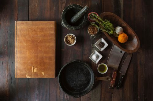 Foto de una mesa con ingredientes listos para cocinar y una tabla de cocina.