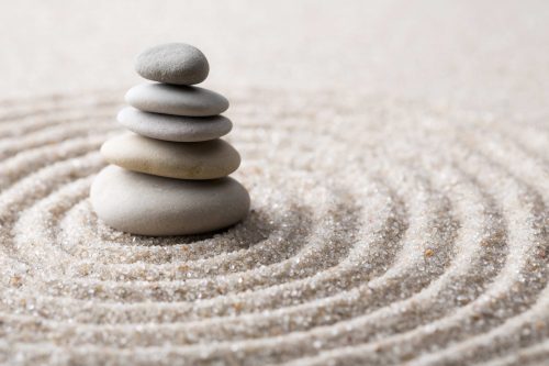 Cinco piedras apiladas sobre arena con círculos concéntricos